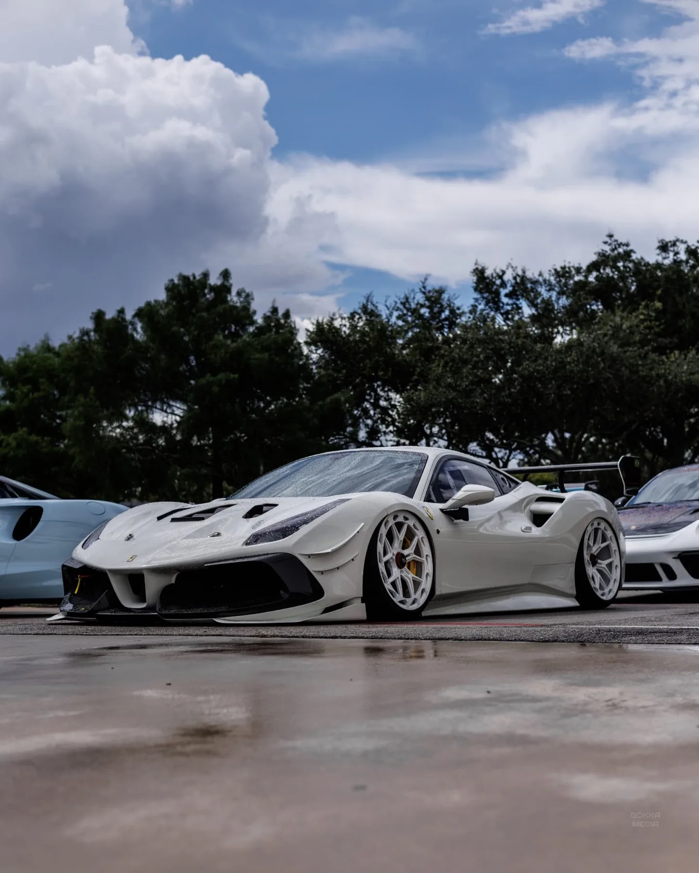 Enrique Diaz's white Ferrari 488 Challenge parked on wet ground