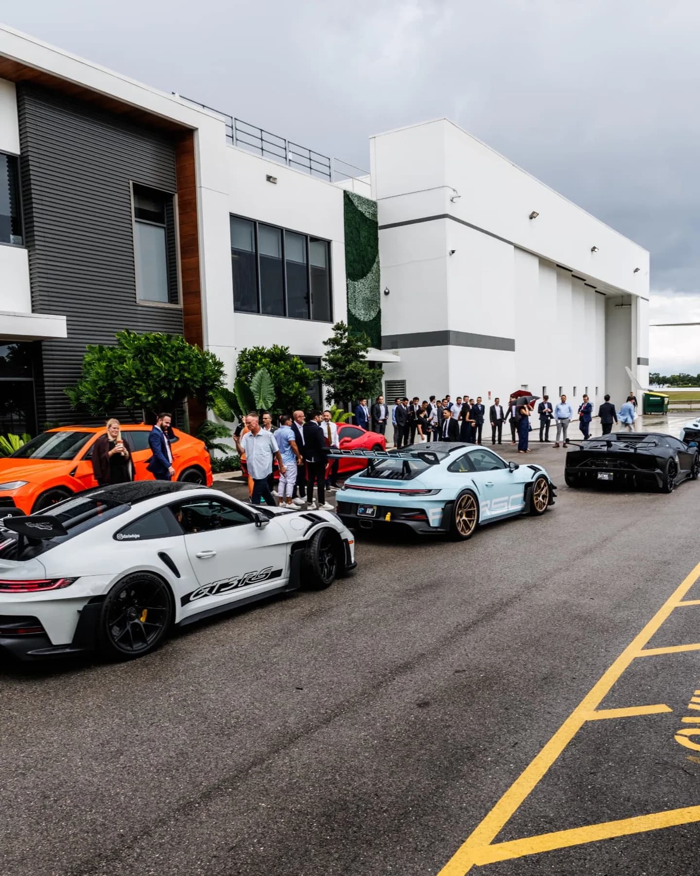 A crowd gathered around the supercars outside the hangar