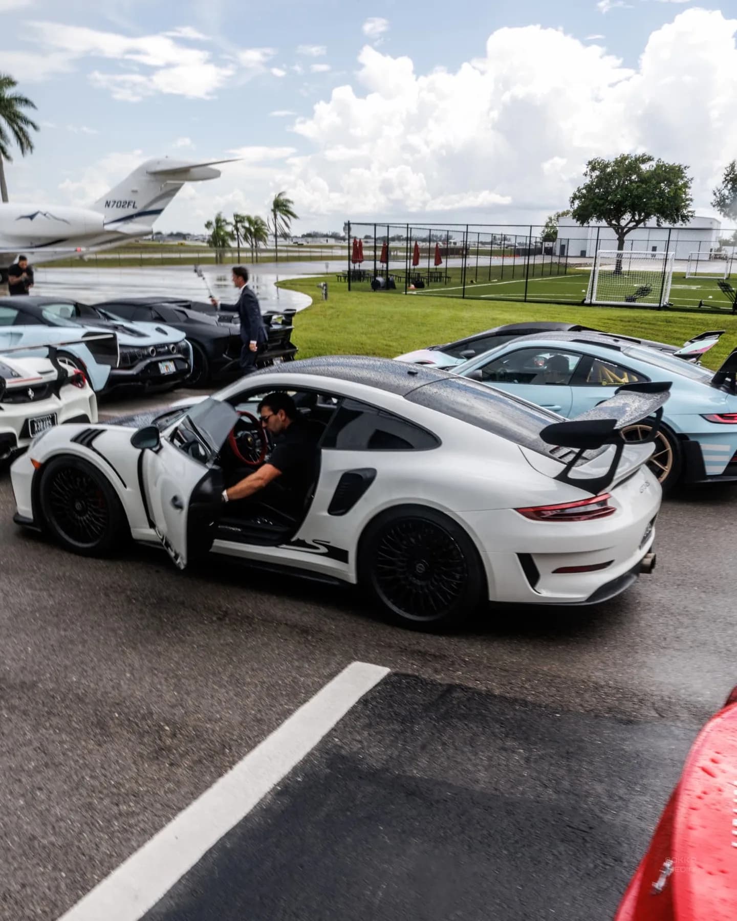 Dao stepping into a white Porsche 911 GT3 RS with a private jet behind