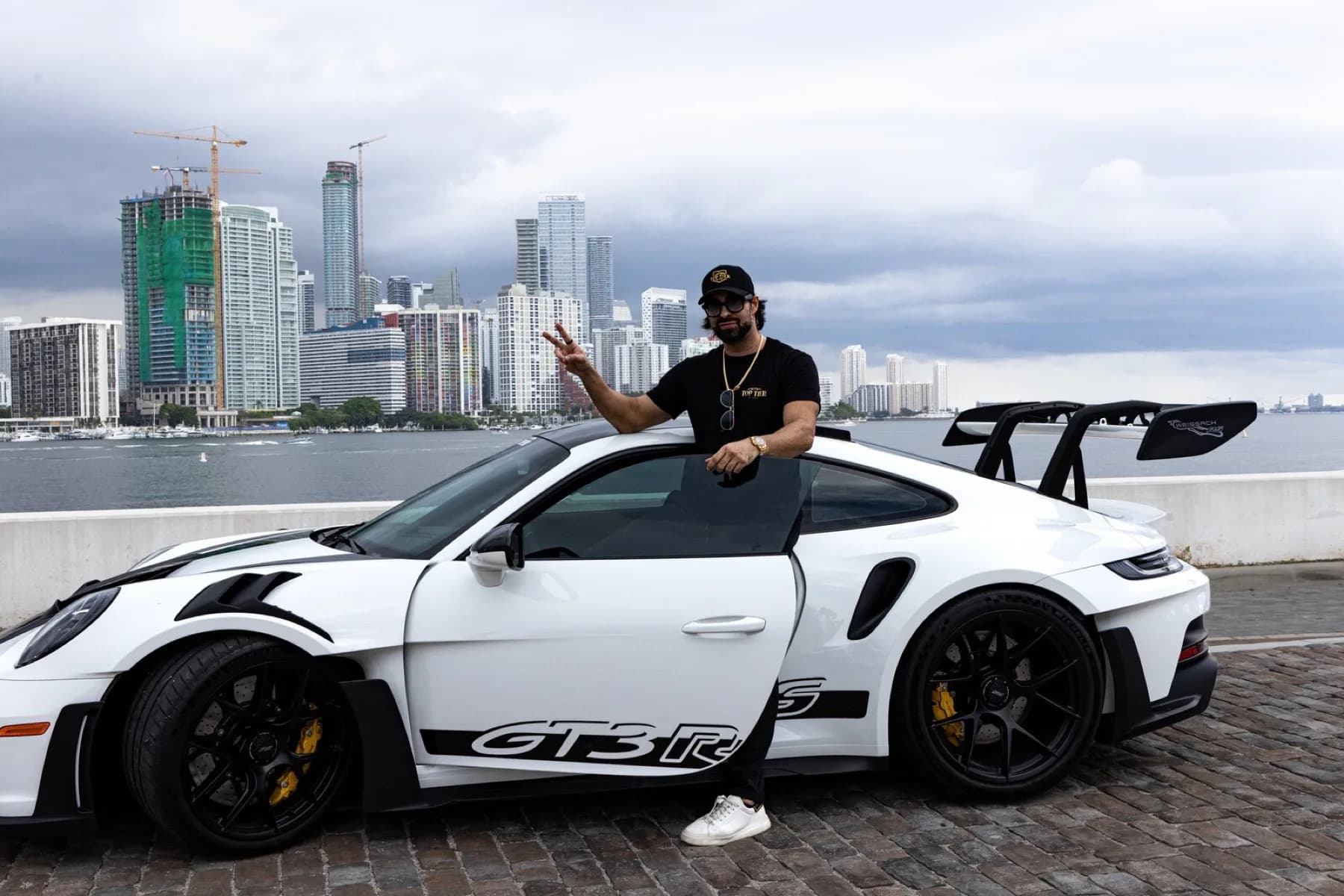Dao standing beside his white Porsche 911 GT3 RS on the Miami waterfront.
