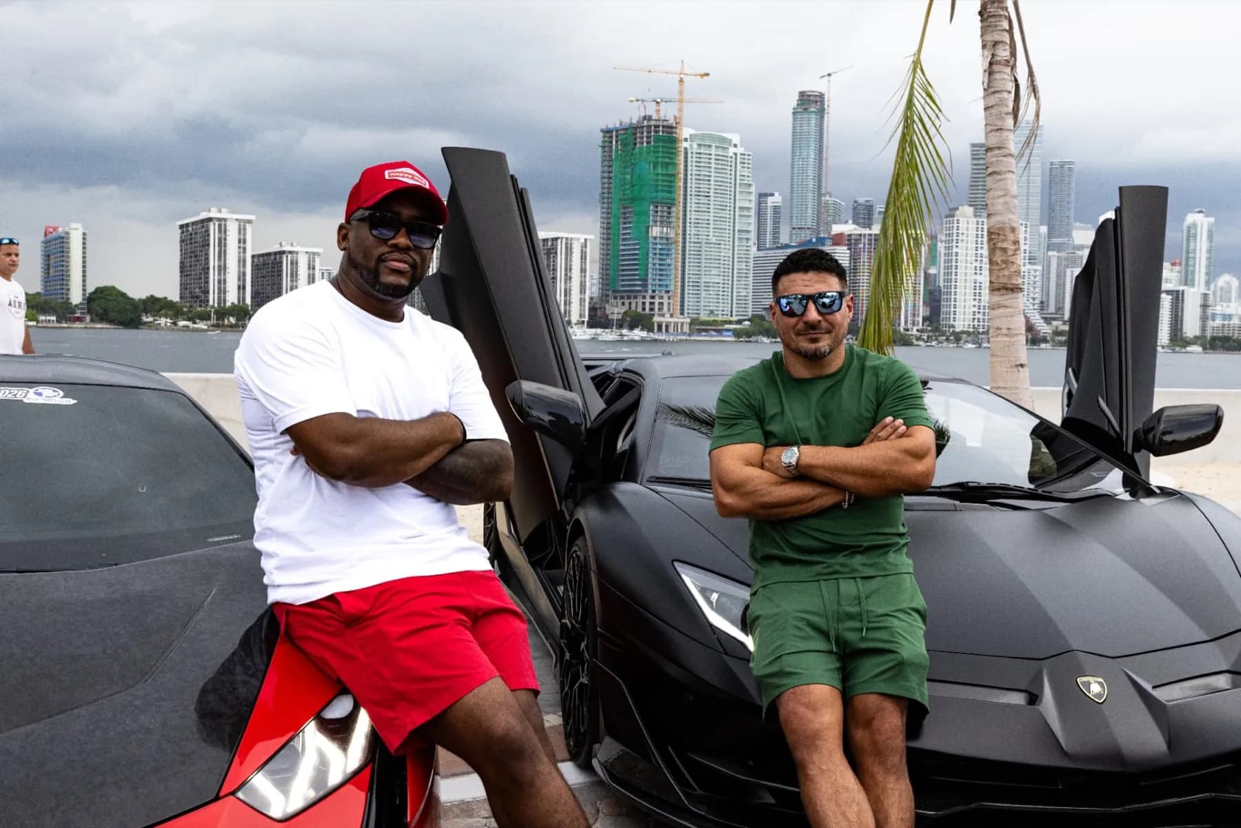 Ricky Harris, left, in white, and Dario Diaz, right, in green, standing in front of their Lamborghinis on the Miami waterfront.