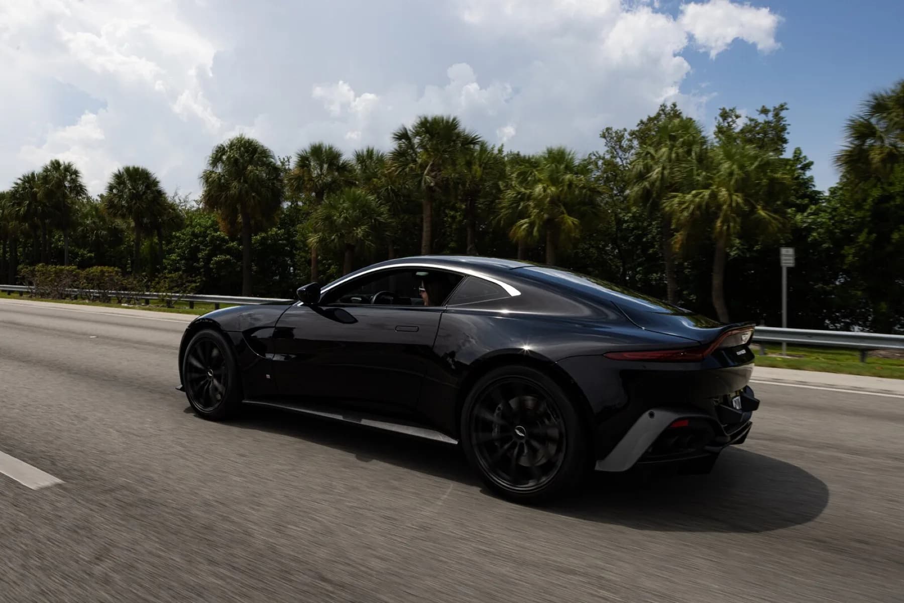 A dark Aston Martin Vantage on the highway.