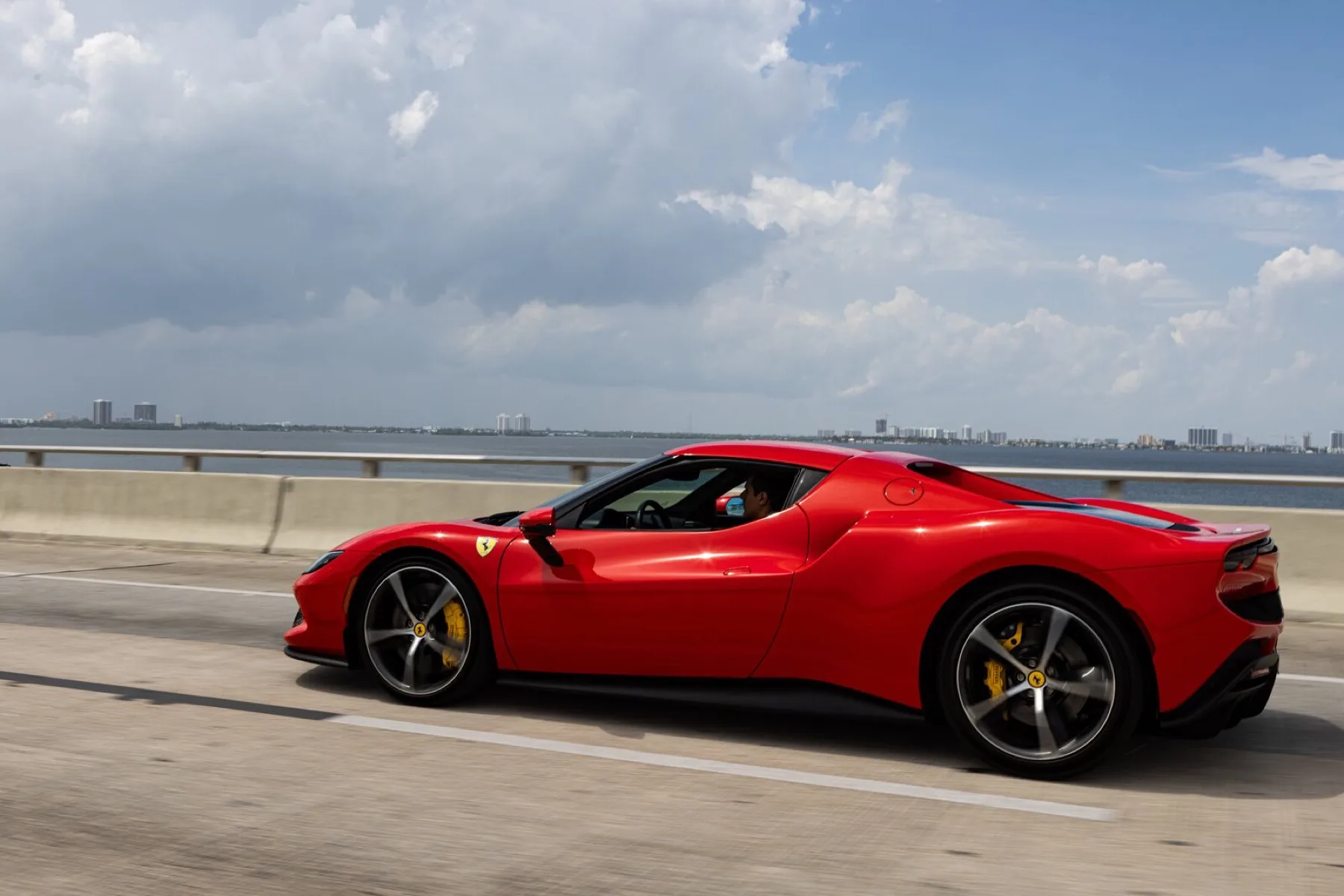 A red Ferrari 296 running along the causeway.