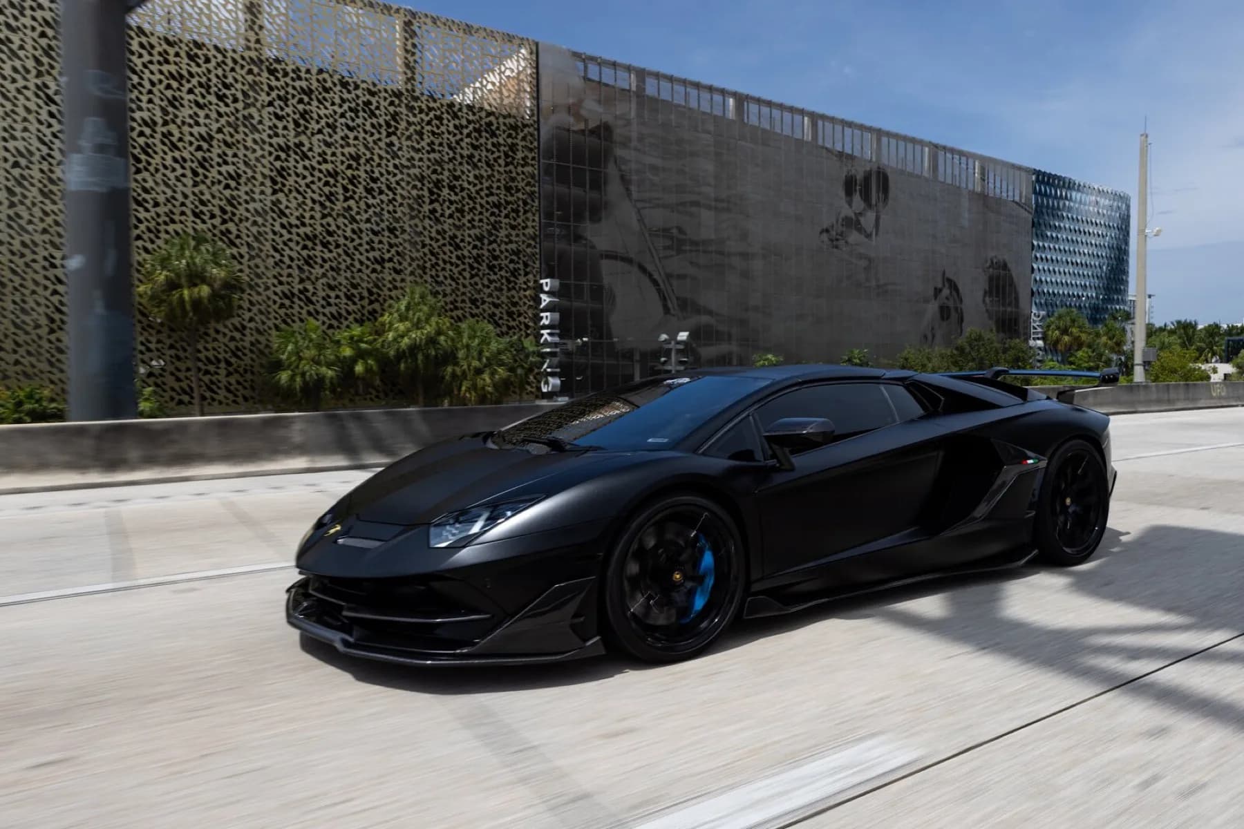 A matte black Lamborghini Aventador SVJ on the highway.
